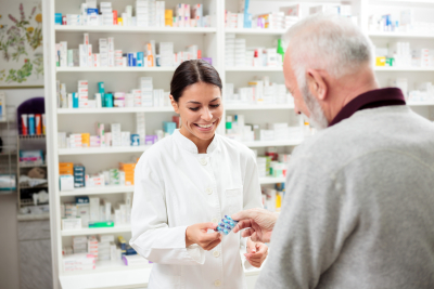 happy pharmacist giving medications to senior man customer