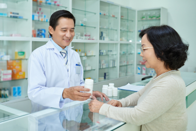 Pharmacist giving tablets to senior female customer